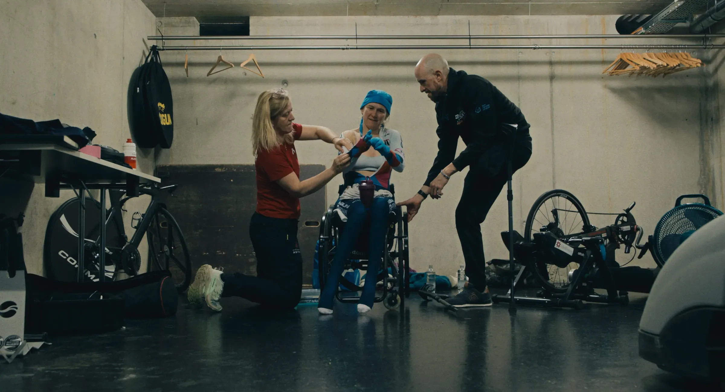 Film still from Breaking Barriers: Svetlana Moshkovich in a training garage, helped by two people before a session